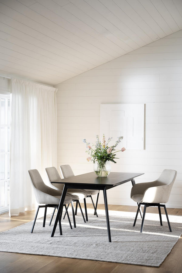 Matgrupp med grå stoppade stolar och svart bord i modern skandinavisk matsal med vita väggar