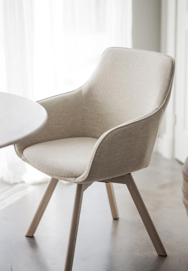 Beige stol med armstöd och träben i modern skandinavisk design för matsal eller kök