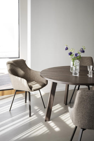 Rund matbord i mörkt trä med grå stolar i modern matsal med naturligt ljus och blommor