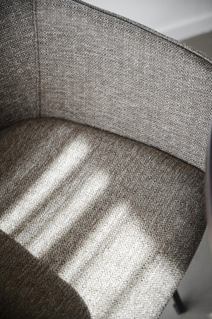 Närbild på grå tygsoffa med synlig vävstruktur och mjuka kuddar i naturligt ljus