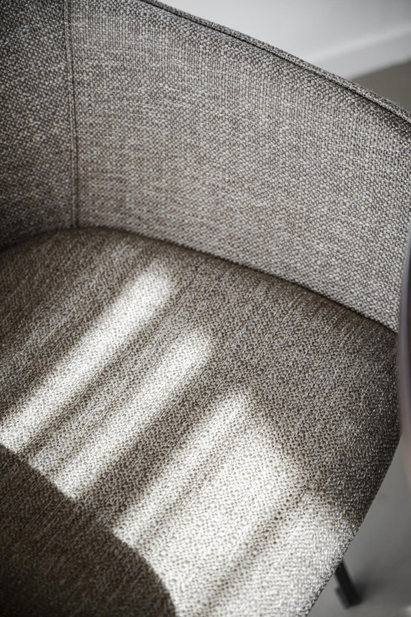 Närbild på grå tygsoffa med synlig vävstruktur och mjuka kuddar i naturligt ljus