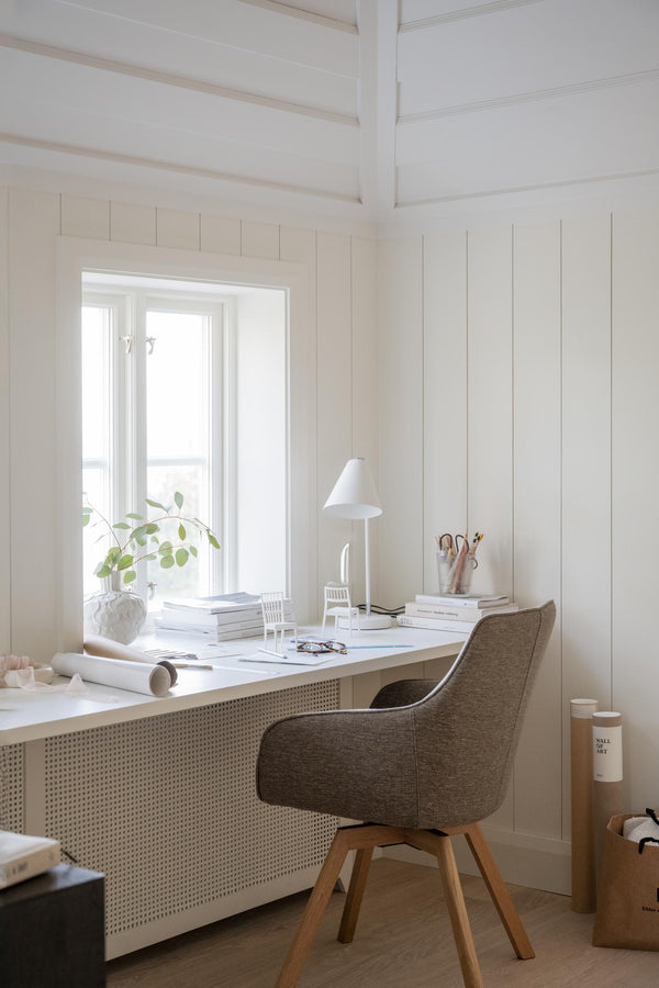 Ljust hemmakontor med vit skrivbordsstol i brunt tyg, vitt skrivbord och skandinavisk inredning