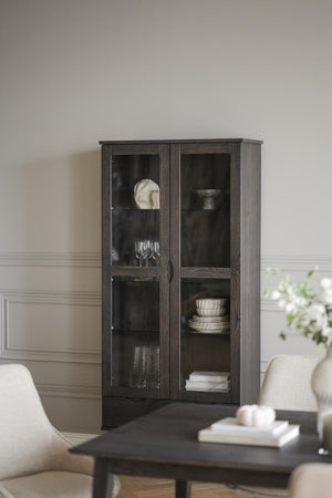 Vitrinskåp i mörkgrått trä med glasdörrar och hyllplan, inrett med porslin och dekorationer i vardagsrum