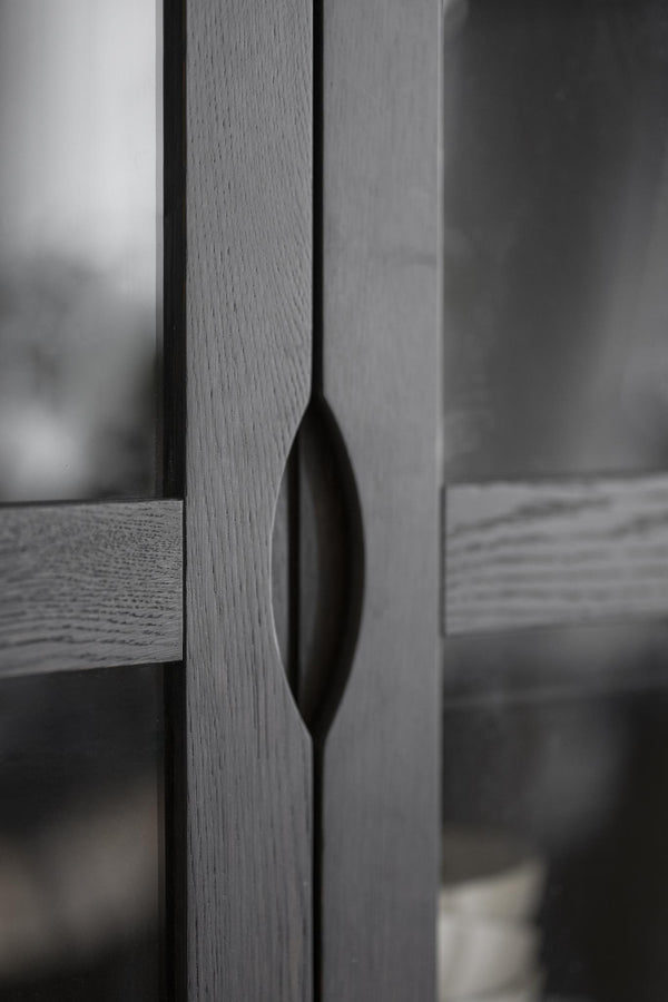 Närbild på modern möbelhandtag i svart metall med elegant oval design monterad på grå skåpslucka