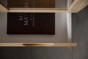 Brun Matt fotopärm med guldtext på hylla i ljust trä med neutral bakgrund