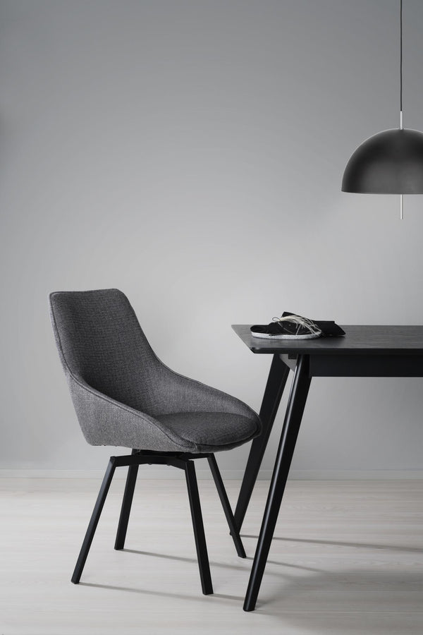 Grå matstol med svarta ben vid matbord med svart taklampa i minimalistisk skandinavisk stil