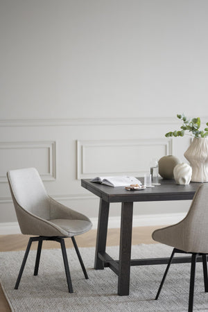 Ljusgrå matstol med svarta ben vid mörkt matbord i modern matsal med vita väggar