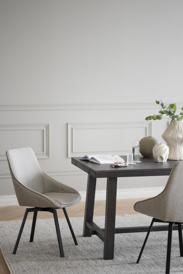 Ljusgrå matstol med svarta ben vid mörkt matbord i modern matsal med vita väggar