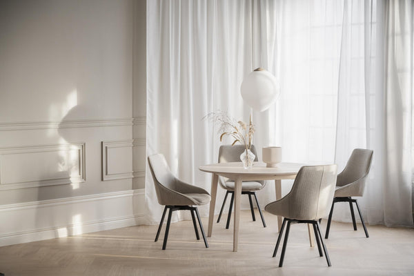 Ljus matgrupp med runt bord och fyra gråbeige stolar i minimalistisk skandinavisk stil
