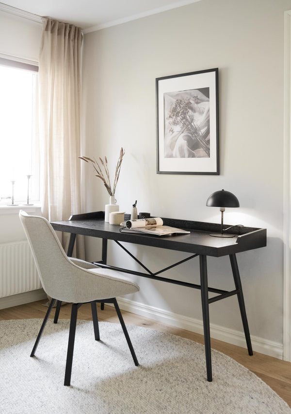 Svart skrivbord med beige stol i minimalistiskt hemmakontor med tavelvägg och gardiner