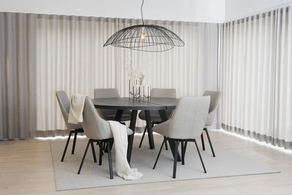 Rund matgrupp i svart med sex ljusgrå stolar och wirelampa i modern matsal med vita gardiner