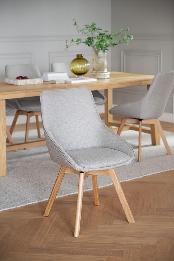 Grå matstol med träben i ljus ek vid matbord i modern skandinavisk stil