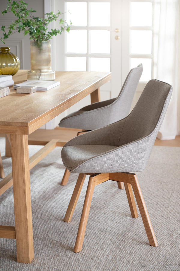 Matgrupp med modern skandinavisk design, ljust trä och grå stoppad stol med träben vid matbord