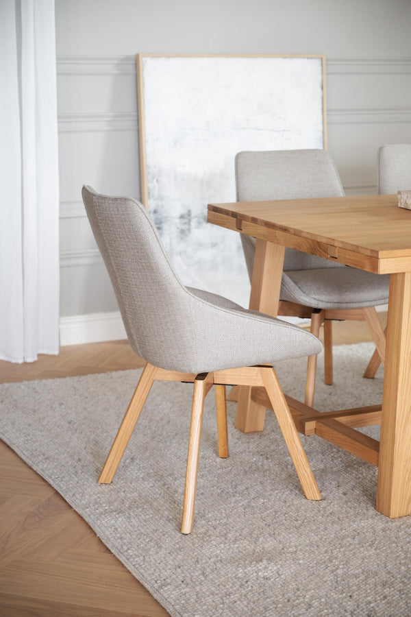 Ljusgrå matstol med träben i ek vid matbord i modern skandinavisk matsalsmiljö