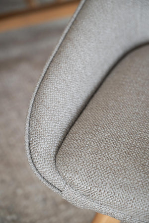 Närbild på armstöd i ljusgrått tyg med diskret textur på modern soffa eller fåtölj