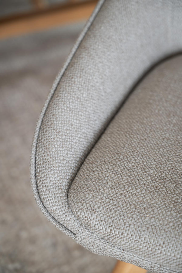 Närbild på armstöd i ljusgrått tyg med diskret textur på modern soffa eller fåtölj
