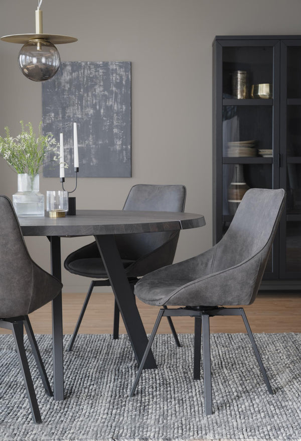 Rund matbord i mörkgrå ek med svarta metallben och grå sammetsstolar i modern matsal