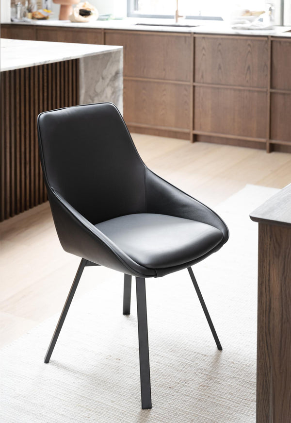 Svart stol med metallben i modernt kök med trägolv och träskåp
