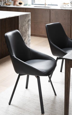 Svarta moderna matstolar med konstläder och metallben vid matbord i kök med trädetaljer