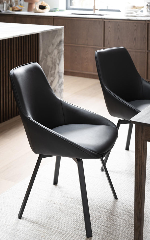 Svarta moderna matstolar med konstläder och metallben vid matbord i kök med trädetaljer