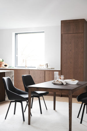 Matbord i mörk ek med svarta stolar i modern minimalistisk matsal med skåpinredning