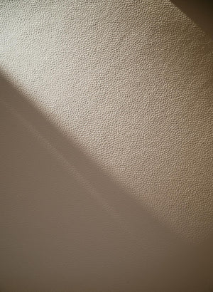 Närbild av vit texturerad vägg med skuggspel från ljuskälla