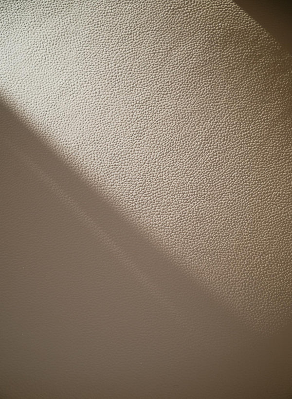 Närbild av vit texturerad vägg med skuggspel från ljuskälla