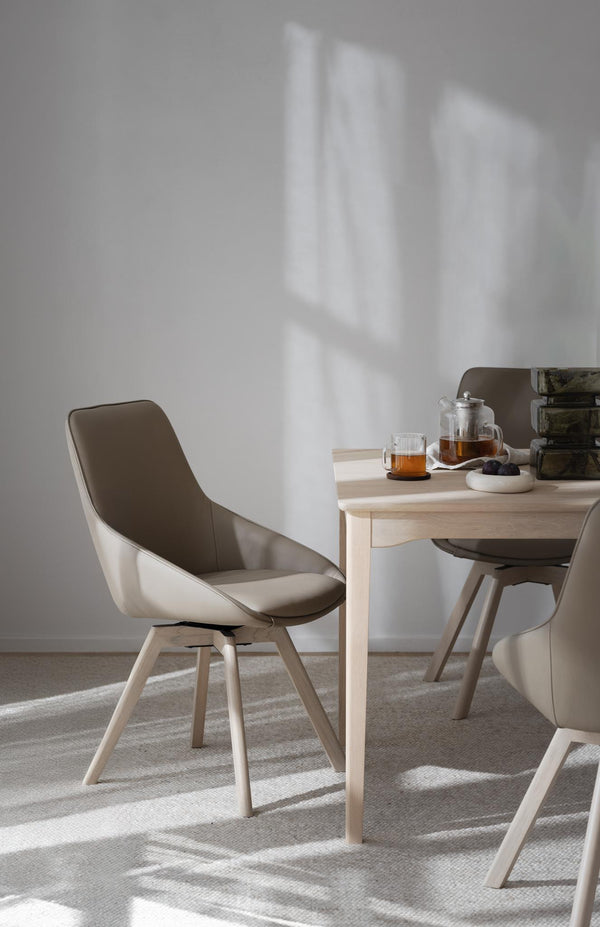 Moderna matstolar i grått och ljust trä vid matbord med tesервис i skandinavisk stil