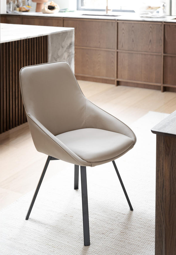 Beige matstol med svarta metallben i modernt kök med träskåp och ljust golv