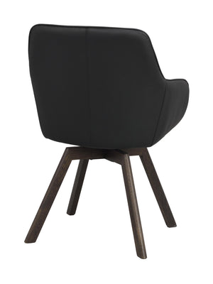 Svart fåtölj med träben i mörkbrun ek, sedd bakifrån med mjukt stoppad rygg och armstöd