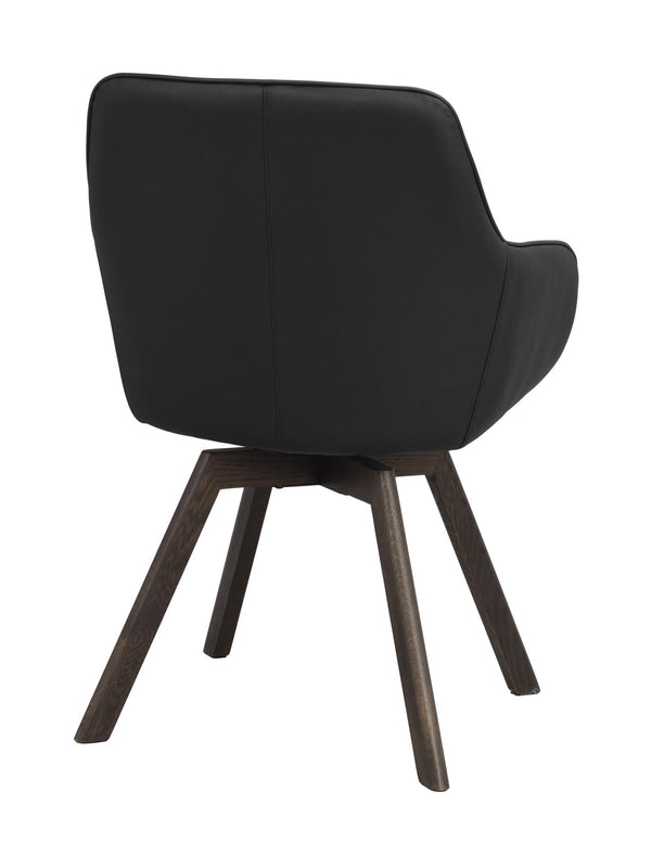 Svart fåtölj med träben i mörkbrun ek, sedd bakifrån med mjukt stoppad rygg och armstöd