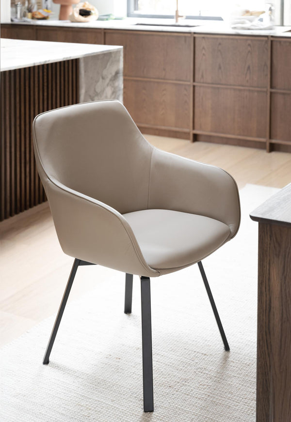 Beige matstol med armstöd och svarta metallben i modernt kök med träskåp