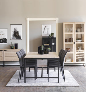 Matbord med stolar i modern matsal med vitrinskåp och tavelkonst på väggarna