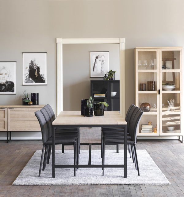 Matbord med stolar i modern matsal med vitrinskåp och tavelkonst på väggarna