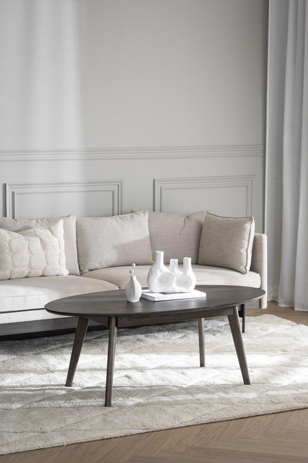 Oval soffbord i mörkt trä med vita vaser i elegant vardagsrum med beige soffa och ljus matta