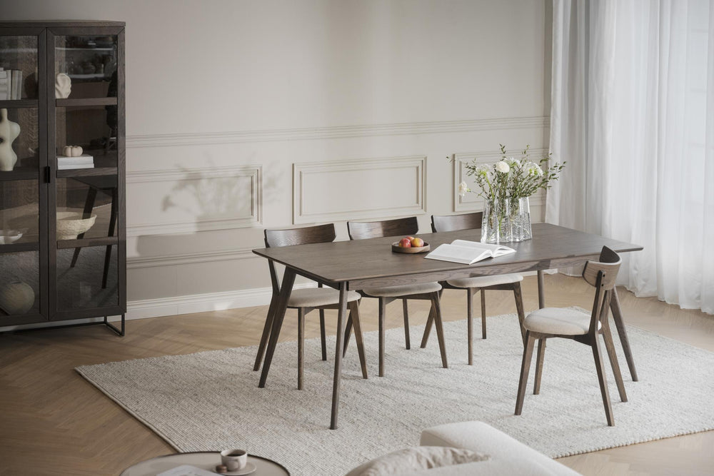 Mörkbrun träbord med smala avsmalnande ben i skandinavisk design, frontvy mot vit bakgrund