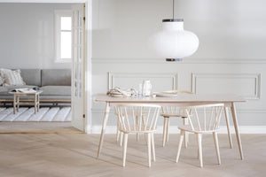 Ljus matplats med ljust trä matbord, stolar och vit taklampa i skandinavisk stil
