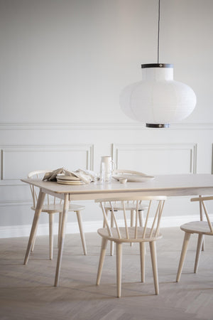 Ljus matgrupp i trä med vita stolar och oval taklampa över matbordet i minimalistisk skandinavisk stil