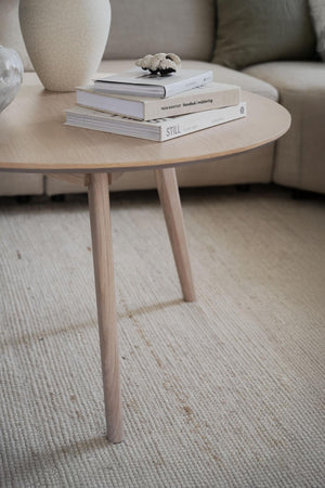 Runt soffbord i ljust trä med böcker och dekoration, skandinavisk design för vardagsrum