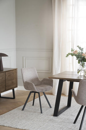 Grå matstol med armstöd och svarta ben vid matbord i modern skandinavisk matsal