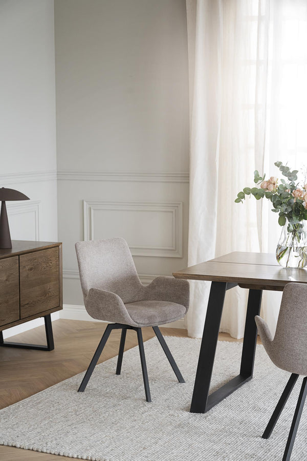 Grå matstol med armstöd och svarta ben vid matbord i modern skandinavisk matsal