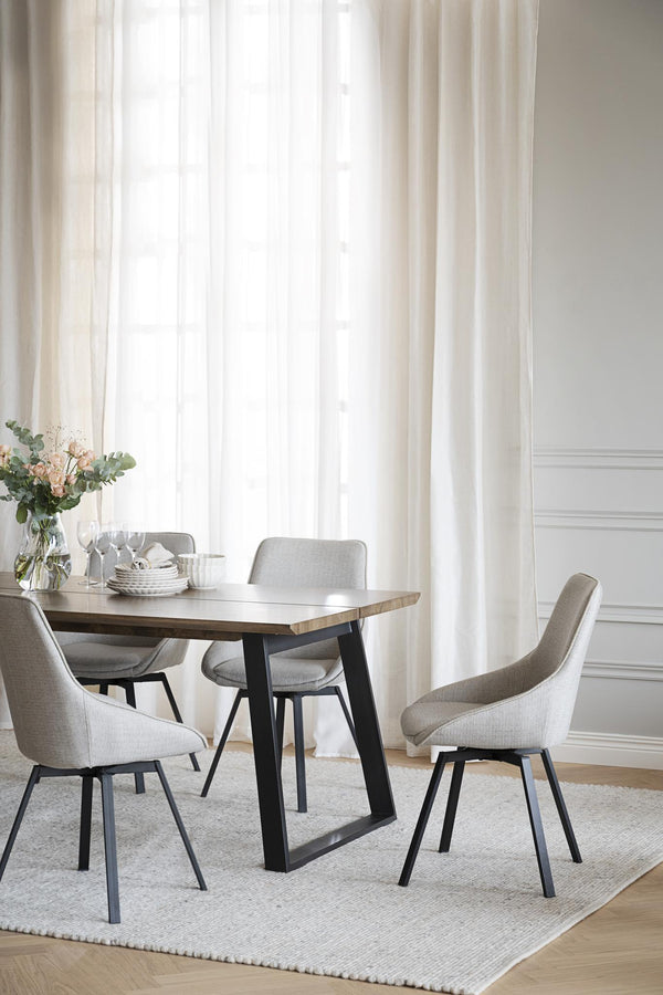 Matgrupp med träbord och grå stolar i modern skandinavisk matsal med ljusa gardiner