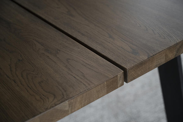 Närbild på massiv ekbordsskiva med synlig trästruktur och naturlig ådring i gråbrun ton