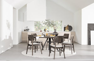 Matgrupp med runt bord och sex stolar i mörkt trä på rund matta i ljust minimalistiskt matrum