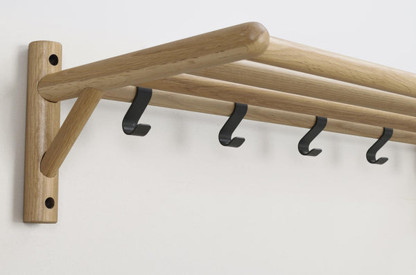 Väggmonterad klädhängare i ek med fyra svarta krokar och triangelformad stötta