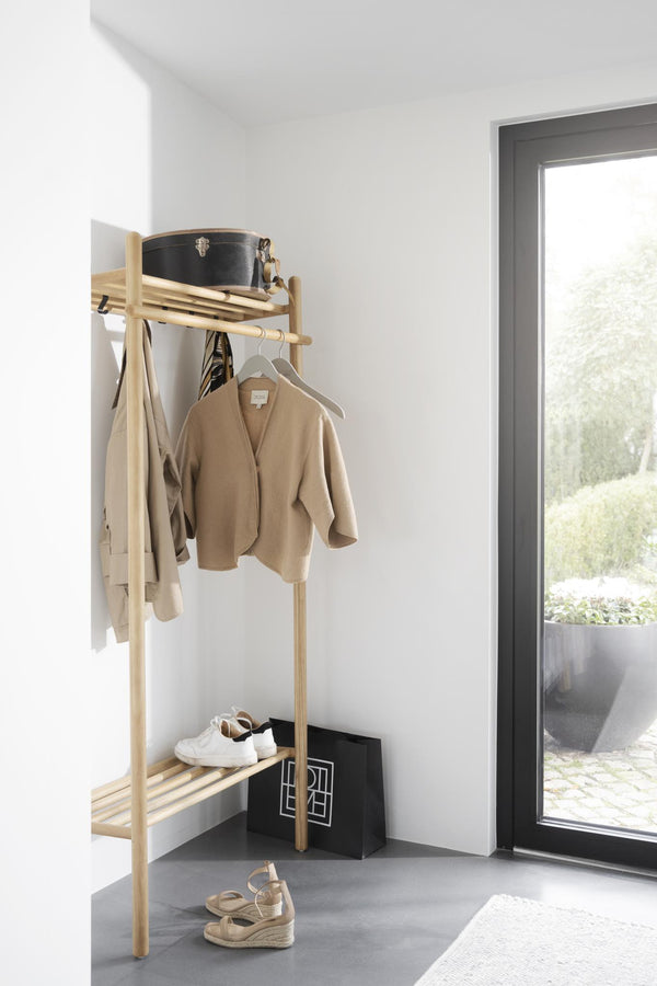 Minimalistisk klädhängare i ljust trä med jackor, hylla för skor och förvaring i modern hall