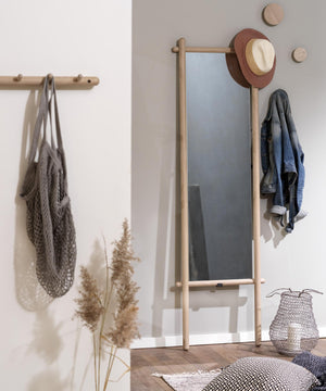 Stående spegel i trä med klädkrokar, dekorerad med hatt och jeansjacka i minimalistisk entré