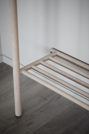 Minimalistisk hallmöbel i ljust trä med rena linjer och hylla för skoförvaring