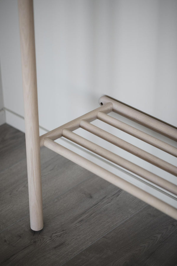 Minimalistisk hallmöbel i ljust trä med rena linjer och hylla för skoförvaring