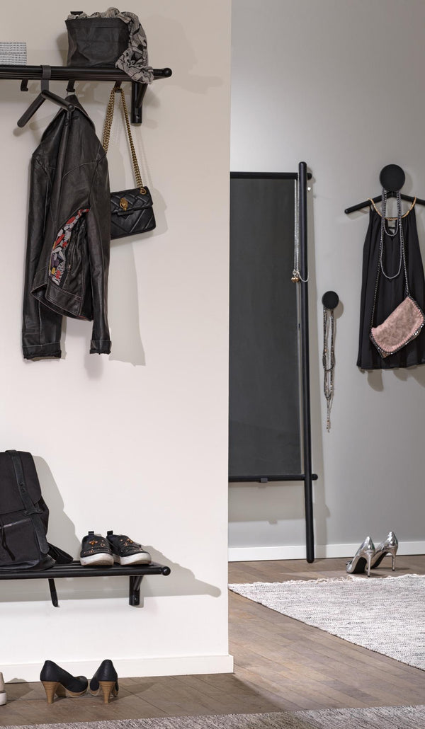 Svart hallmöbel med klädhängare, hylla och krokar med jacka, väskor och skor i modern skandinavisk stil